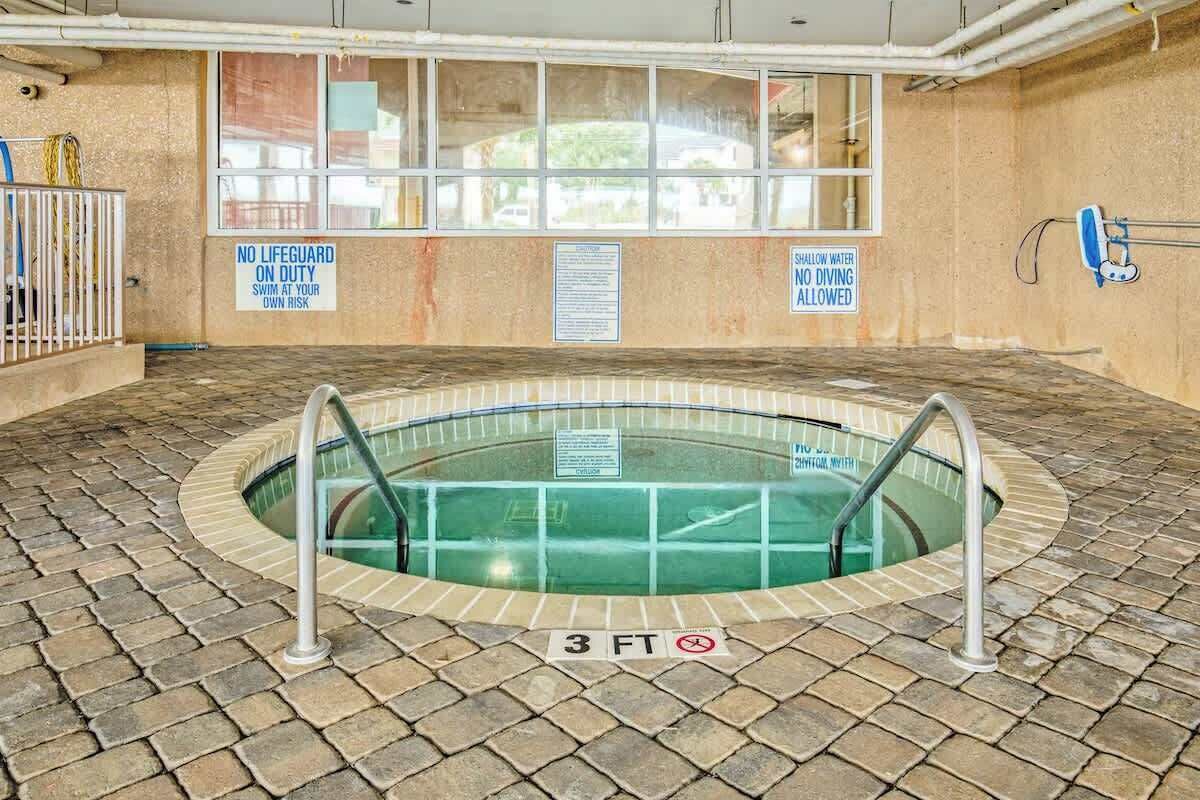An indoor swimming pool with a 3 FT depth sign, surrounded by a brick floor, with safety signs on the walls.