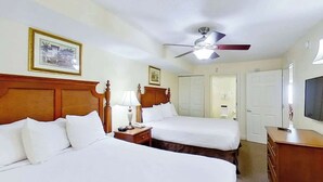 Ein Hotelzimmer mit zwei Betten, einem Deckenventilator, einem Fernseher und einer hölzernen Kommode.