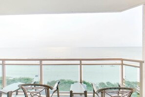 A balcony with a table and chairs, overlooking a body of water.