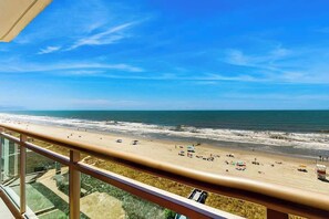 A beach view from a balcony with a clear sky, sandy beach, and ocean. - Bahama Sands Unit 0708 (North Myrtle Beach)