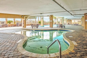 An indoor swimming pool with a brick border, surrounded by lounge chairs and tables. - Bahama Sands Unit 0708 (North Myrtle Beach)