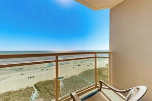 Ein Balkon mit Blick auf einen Strand und eine Straße.