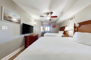 A hotel room with a bed, a television, a ceiling fan, and a wall-mounted artwork. - Bahama Sands Unit 0707 (North Myrtle Beach)