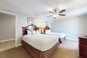 A hotel room with a large bed, a ceiling fan, and a dresser. - Bahama Sands Unit 0802 (North Myrtle Beach)