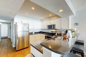 A modern kitchen with stainless steel appliances, white cabinetry, and a granite countertop. - Bahama Sands Unit 0806 (North Myrtle Beach)