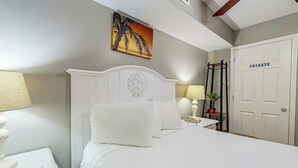 A hotel room with a bed, bedside tables, a lamp, a painting, and a private door. - Bahama Sands Unit 0807 (North Myrtle Beach)