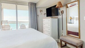 A hotel room with a large bed, a television, a bench, a dresser, and a view of the ocean. - Bahama Sands Unit 0807 (North Myrtle Beach)
