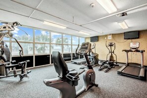 A gym with various exercise equipment, large windows, and a television on the wall. - Bahama Sands Unit 0807 (North Myrtle Beach)