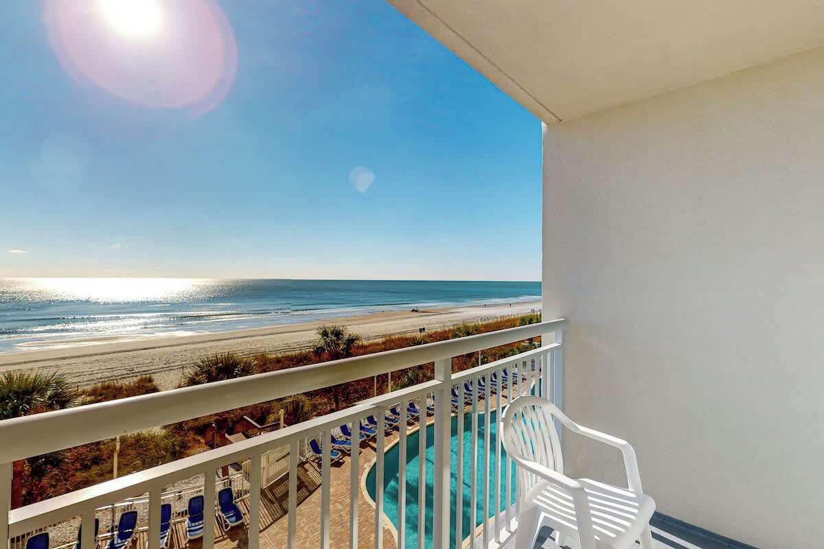 Ein Balkon mit Blick auf Strand und Meer.