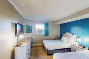 A hotel room with a bed, bedside tables, a desk, and a window with curtains. - Bay Watch Resort 0313 (North Myrtle Beach)