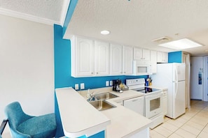 A modern kitchen with white cabinets, a sink, a stove, and a refrigerator. - Bay Watch Resort 0313 (North Myrtle Beach)