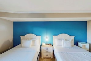 A hotel room with two single beds, a bedside table with a lamp, and a nightstand with a phone. - Bay Watch Resort 0313 (North Myrtle Beach)