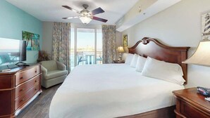 Ein Hotelzimmer mit einem großen Bett, einem Deckenventilator, einem Fernseher, einem Sofa und Blick ins Freie.