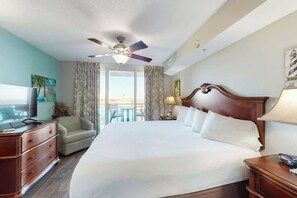 Ein Hotelzimmer mit einem großen Bett, einem Deckenventilator, einem Fernseher, einem Sofa und Blick ins Freie.