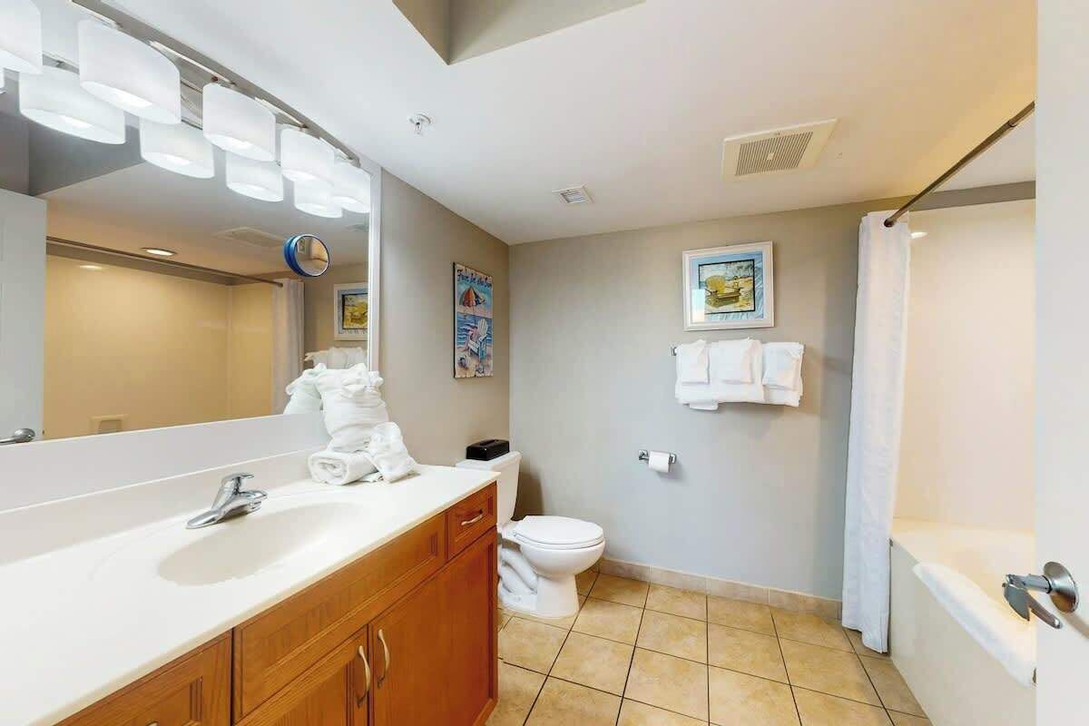 Une salle de bain équipée d’un lavabo, d’un miroir, de toilettes et d’une douche.