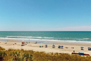 A beach with umbrellas and a lifeguard tower. - Bay Watch Resort 0407 (North Myrtle Beach)