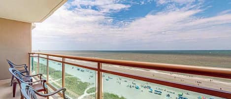 A balcony with a view of a beach and the ocean.