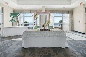 Ein Zimmer mit festlich gedecktem Tisch, großen Fenstern und Blick auf den Strand.