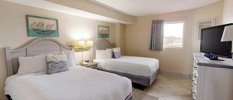 A hotel room with two beds, a television, and artwork on the walls.