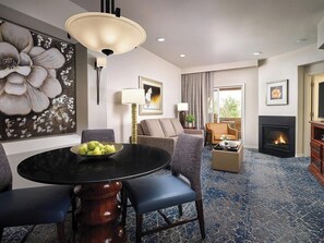Ein Hotelzimmer mit einem runden Esstisch, einer Sitzecke, einem Kamin und einem großen floralen Wandbild.