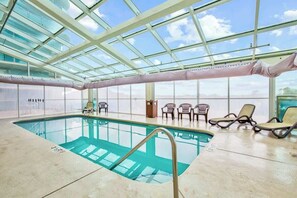 An indoor swimming pool with clear glass ceilings, lounge chairs, and a view of the sky. - Bahama Sands Unit 0902 (North Myrtle Beach)