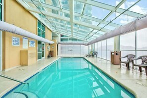 Ein Hallenbad mit klaren Glasdecken, Sicherheitsschildern und Blick auf den Himmel.