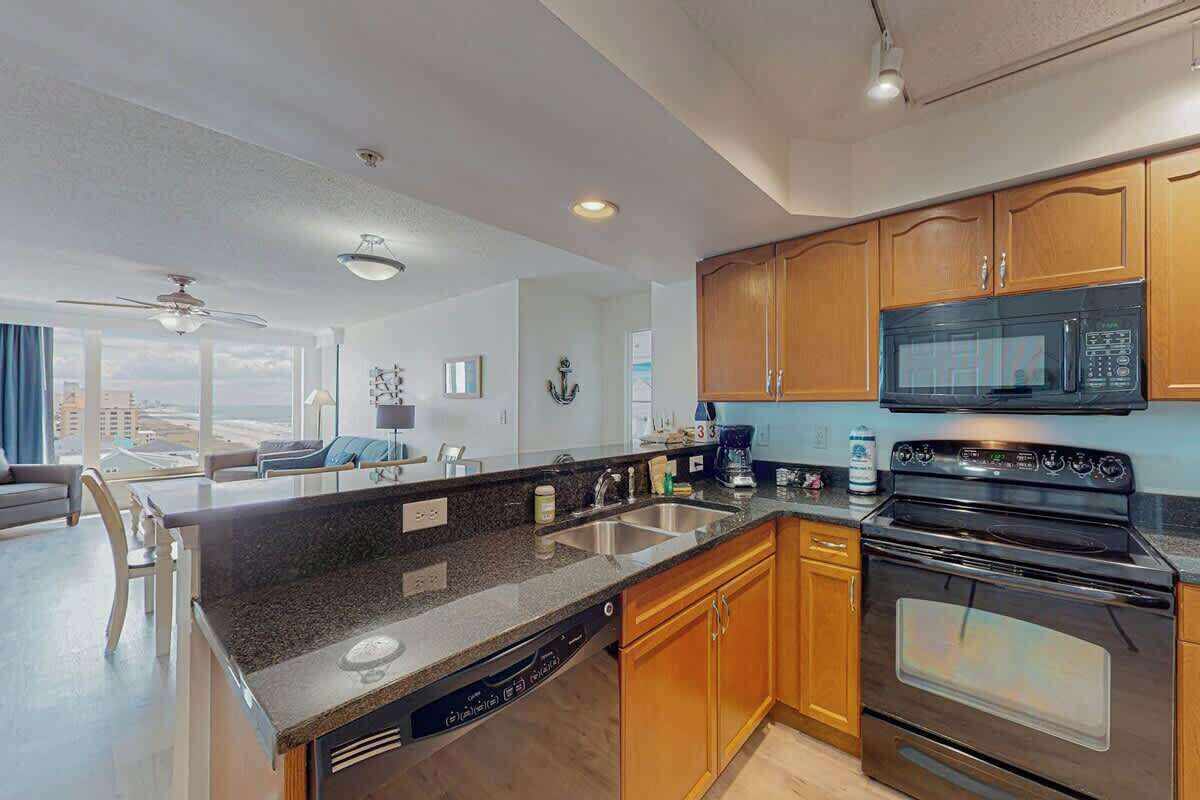 A modern kitchen with granite countertops, stainless steel appliances, wooden cabinets, and a view of the city.