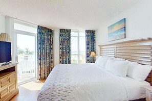 Ein Hotelzimmer mit Bett, Fernseher, Schreibtisch und Vorhängen.