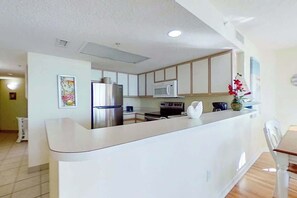 Eine moderne Küche mit Kochinsel, Edelstahlgeräten und einem Essbereich mit Holztisch und Stühlen.
