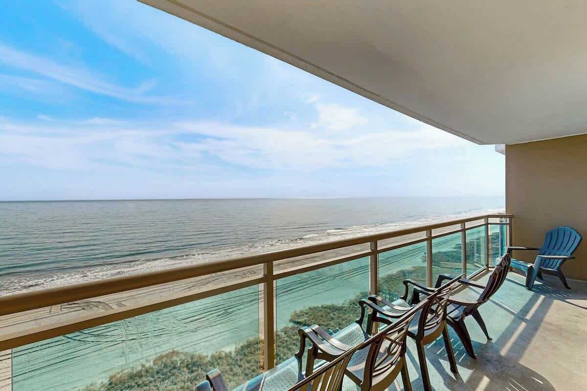 Un balcon avec vue sur l’océan, aménagé avec des chaises et une table.