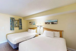 Ein Hotelzimmer mit zwei Einzelbetten, einem Nachttisch mit Lampe, einem Spiegel und zwei gerahmten Bildern an der Wand.