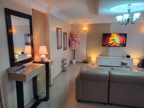 A modern living room with a sofa, a TV, a fireplace, and a mirror. - Safe Haven (Douala)