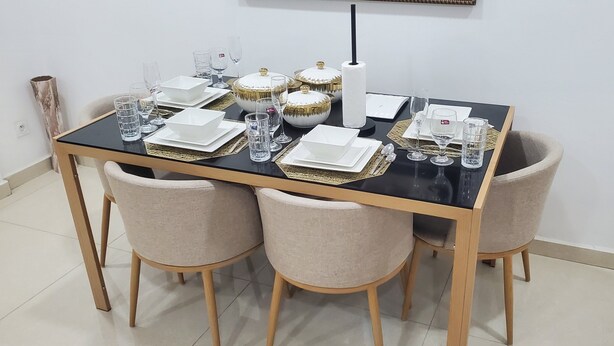 Une table à manger dressée avec des assiettes, des verres et des bols décoratifs.