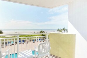 A balcony with a view of the beach, a pool, and lounge chairs. - Bay Watch Resort 0207 (North Myrtle Beach)