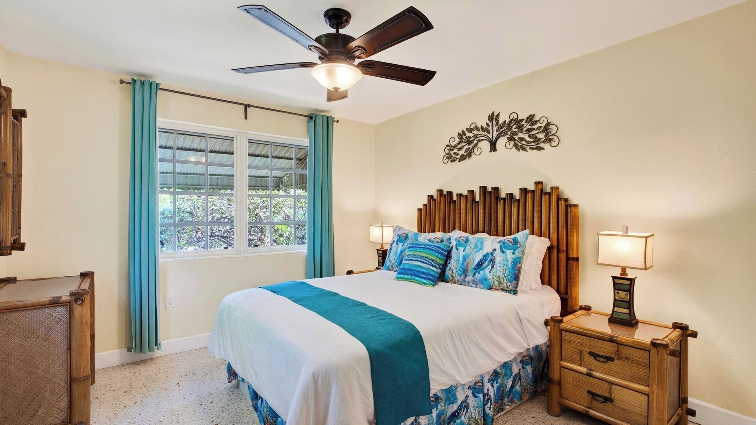 A bedroom with a bed, a nightstand, a wall-mounted decorative piece, and a ceiling fan.
