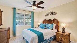 A bedroom with a bed, a nightstand, a wall-mounted decorative piece, and a ceiling fan. - Buttonwood Corner by Avantstay Midtown Key West Private Pool + Tropical Patio Near Beaches (Key West)