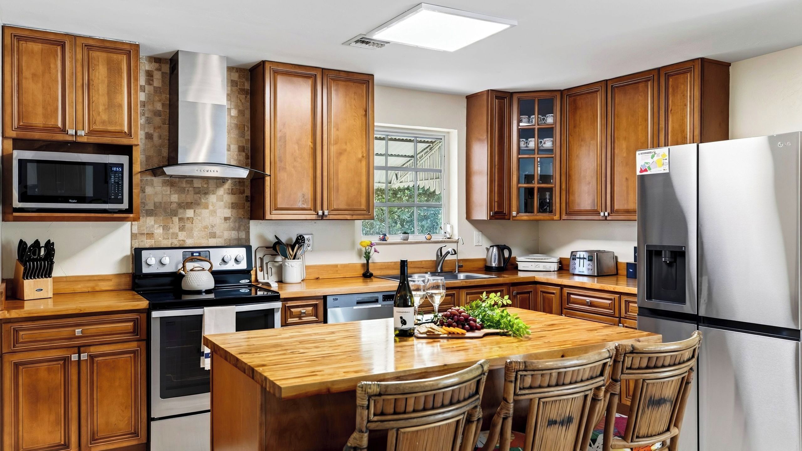 Una cocina moderna con armarios de madera, electrodomésticos de acero inoxidable y una isla central con asientos.