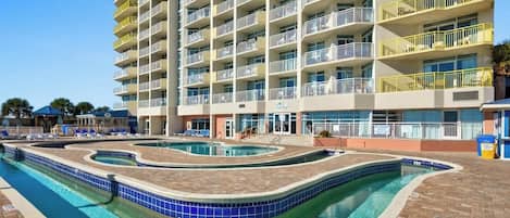 Ein mehrstöckiges Hotel mit Poolbereich, der ein gewelltes Design und eine maximale Tiefe von 90 Zentimetern aufweist.