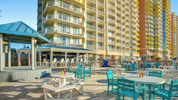 Un resort con zonas de estar al aire libre, un pabellón cubierto y un edificio alto con balcones.