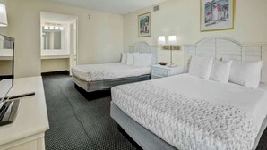 Habitación de hotel con dos camas, un escritorio y un espejo de baño.