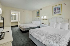 Ein Hotelzimmer mit zwei Betten, einem Schreibtisch und einem Badezimmerspiegel.