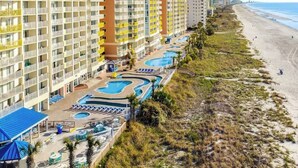 Un hotel frente a la playa con varias piscinas, playa y vista al océano.