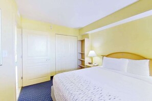 A hotel room with a bed, a nightstand, a lamp, and a wardrobe. - Bay Watch Resort 0505 (North Myrtle Beach)
