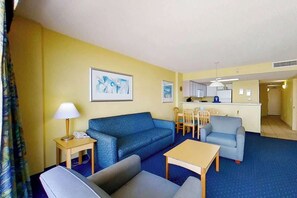 Ein Hotelzimmer mit einem blauen Sofa, einem kleinen Tisch, einer Lampe, einem Telefon und einem Gemälde an der Wand.
