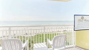 A balcony with white chairs overlooking a beach. A sign on the wall reads 'Bay Watch Resort - A Conference Center.' - Bay Watch Resort 0505 (North Myrtle Beach)