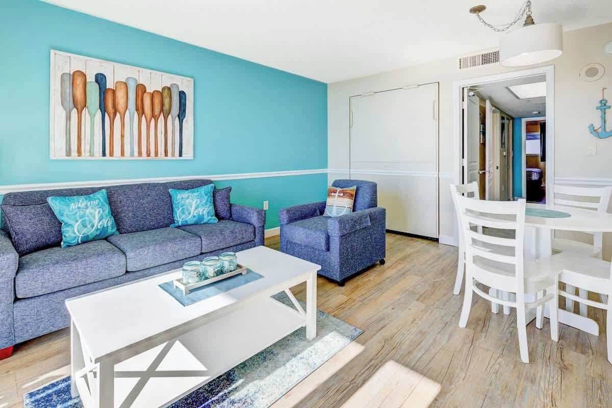 A living room with a sofa, armchairs, a coffee table, and a dining table with chairs.