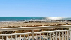 A beach view from a balcony with a railing, a clear sky, and the ocean in the background. - Bay Watch Resort 0507 (North Myrtle Beach)