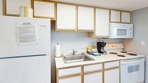 A compact kitchen with a refrigerator, microwave, stove, and sink. - Bay Watch Resort 0507 (North Myrtle Beach)