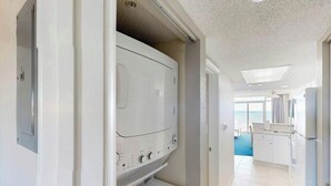 A laundry room with a washer and dryer, a kitchen area, and a view of the ocean. - Bay Watch Resort 0513 (North Myrtle Beach)