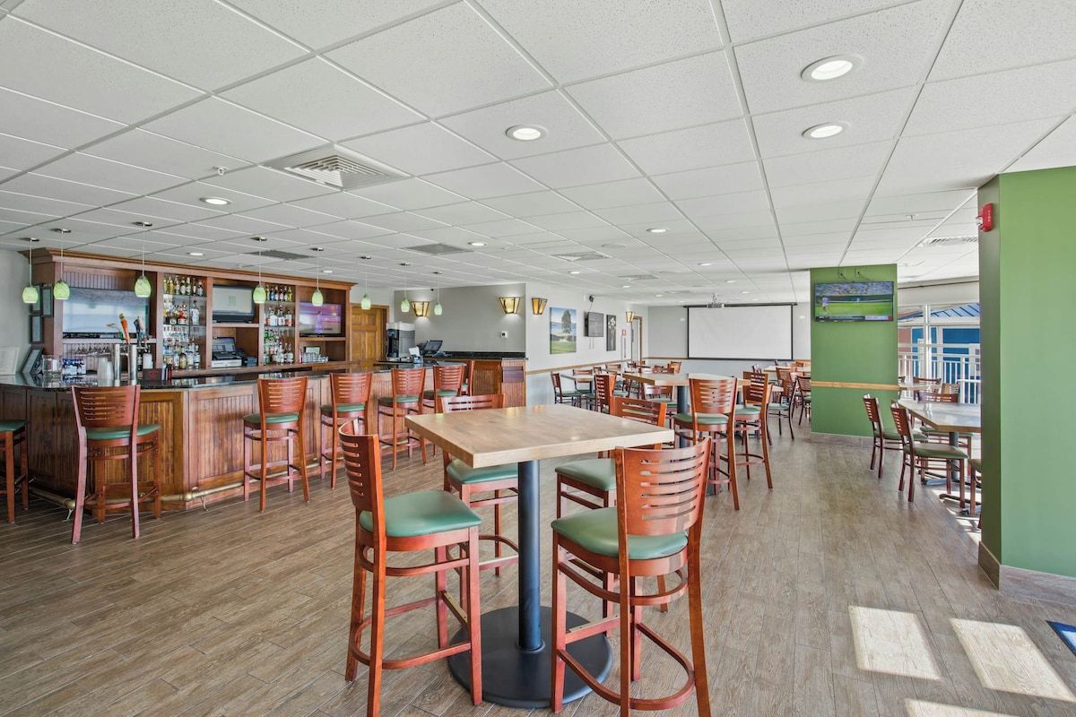 Un restaurant doté de nombreuses tables et chaises, d’un bar et d’un comptoir avec un présentoir.